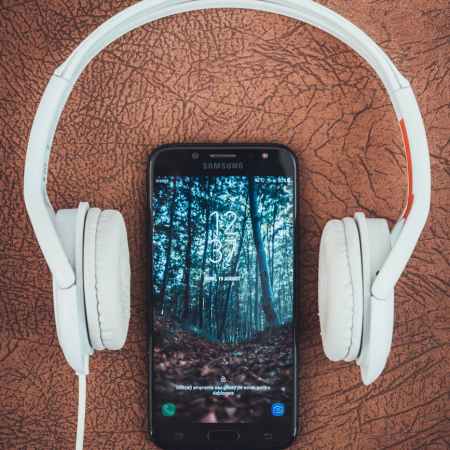 turned on black samsung smartphone between headphones